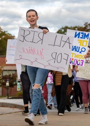 A student holds a sign that reads "All rise for justice" during a Women's March